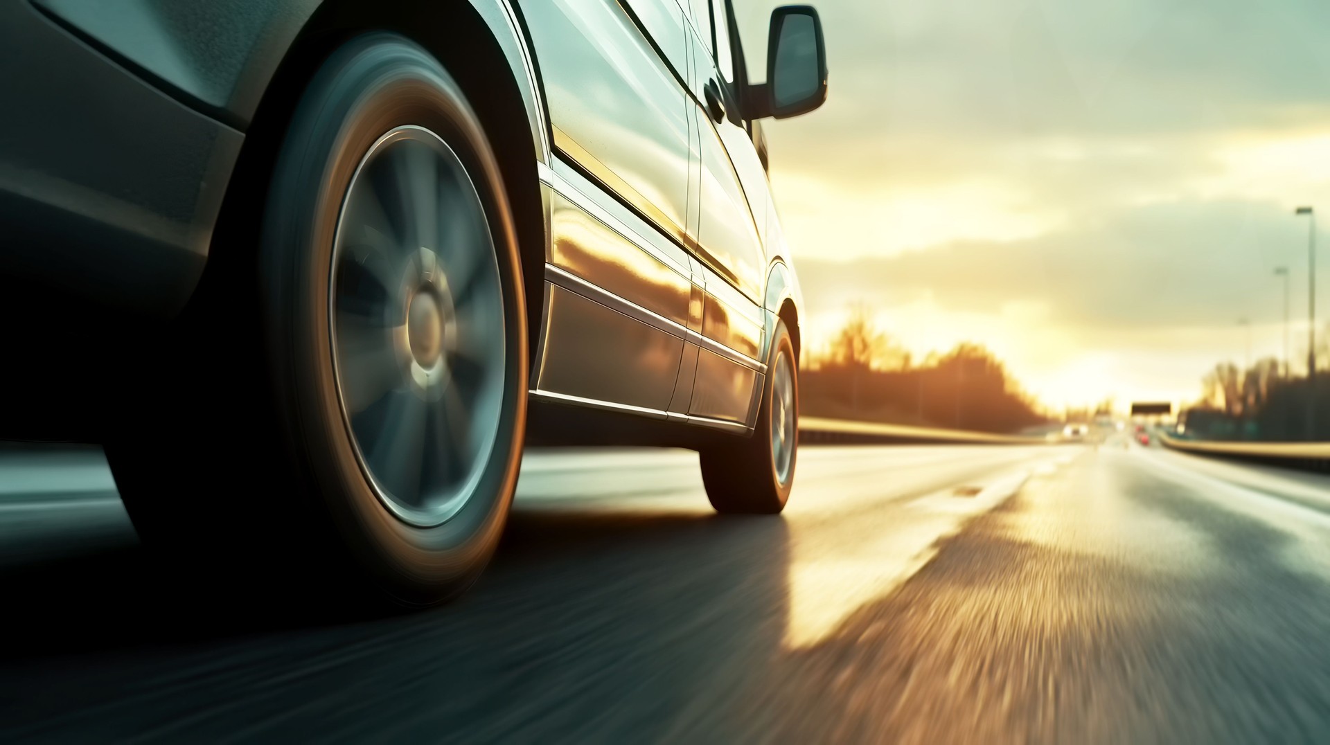 Car rushes along the highway at sunset , low angle side view