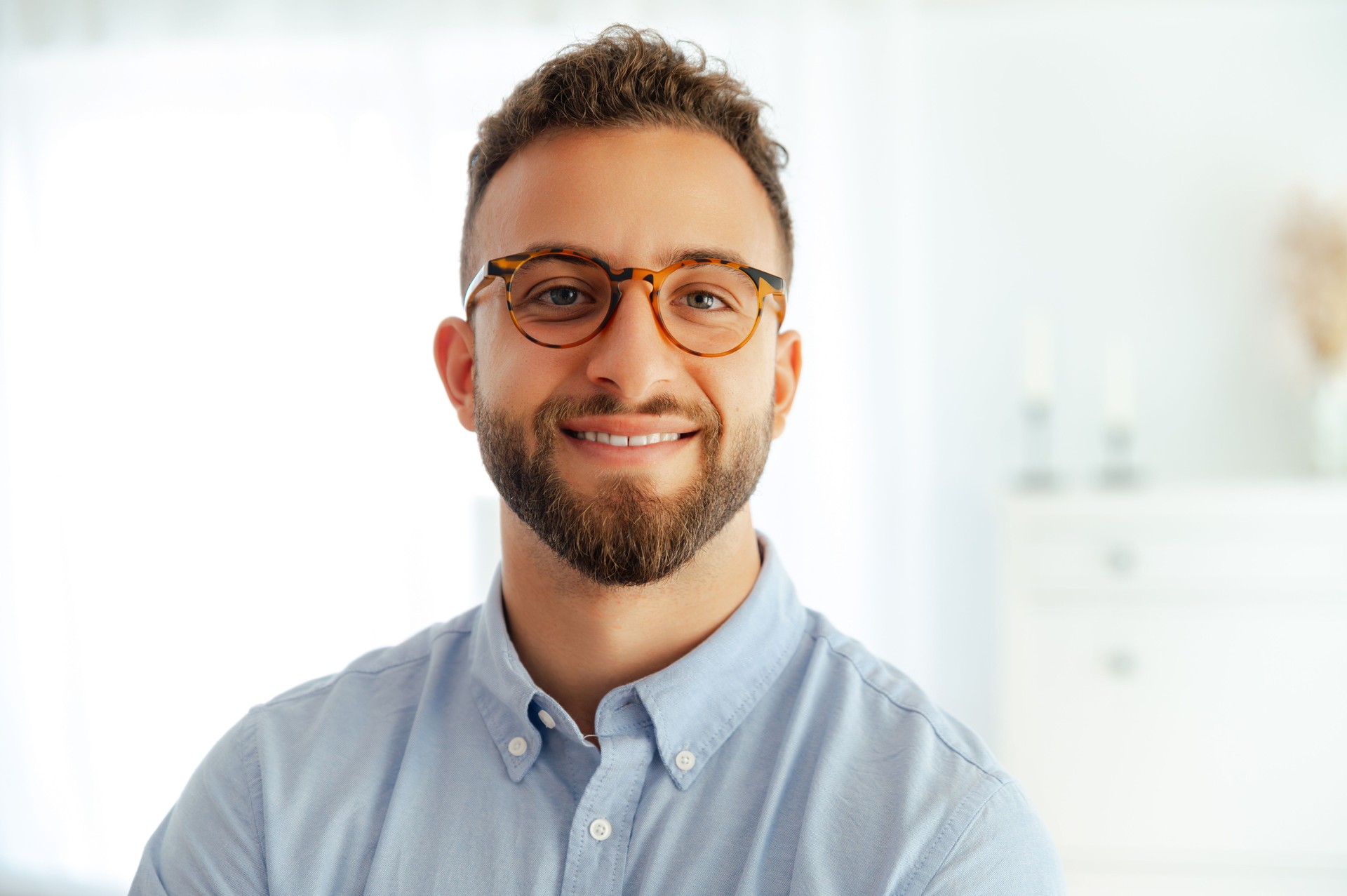 Foto de primer plano de un exitoso hombre de negocios caucásico o árabe atractivo con gafas, de pie con confianza en una oficina moderna, mostrando positividad y disposición para nuevos desafíos, sonrisas a la cámara